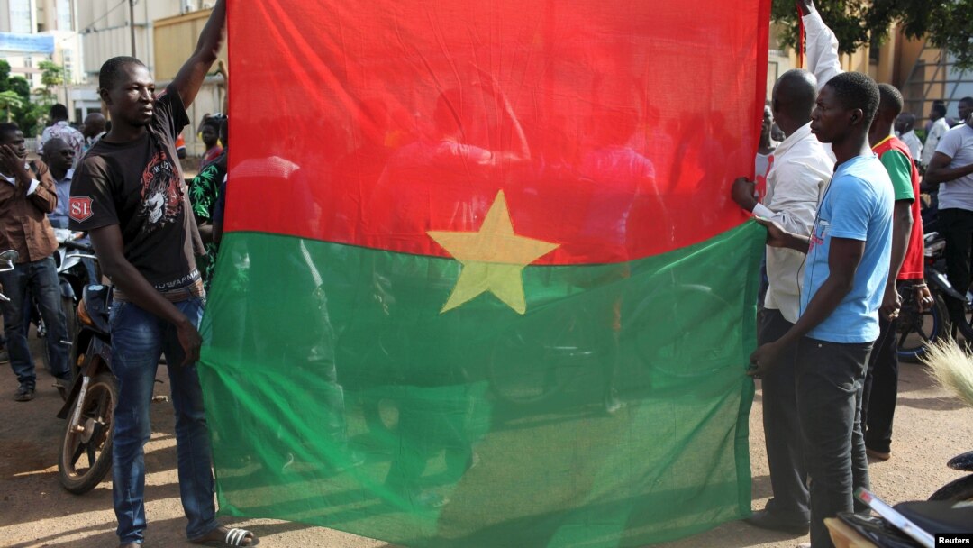 Warga melakukan unjuk rasa anti-kudeta dengan membentangkan bendera nasional Burkina Faso di ibukota Ouagadougou, Selasa (22/9).