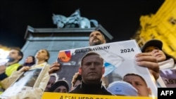 FILE — People hold portraits of the late Russian opposition leader Alexei Navalny, who died in a Russian Arctic prison, as they gather to pay their tribute during a candle vigil in downtown Zagreb on February 23, 2024.