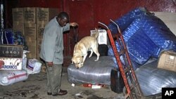 A police dog handler allows his sniffer dog to check out the luggage and goods which lie outside the Kampala-bound bus after the bomb blast in Nairobi, Kenya, Dec 20, 2010