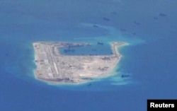 ພວກກຳປັ່ນດູດຊາຍ ຂອງຈີນ ປາກົດວ່າ ເຫັດໄດ້ຢູ່ໃນນ່ານນ້ຳ ອ້ອມບໍລິເວນ ໂຂດຫີນ Fiery Cross Reef ໃນເຂດທີ່ມີການຂັດແຍ້ງກັນ ທີ່ໝູ່ເກາະ Spratly Islands ໃນທະເລຈີນໃຕ້ ຢູ່ໃນພາບນີ້ ຖ່າຍໂດຍ ເຮືອບິນສອດແນມ P-8A Poseidon, ວັນທີ 21 ພຶດສະພາ 2015.