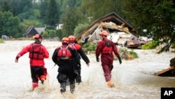 FILE - Firefighters walk through a flooded road of Jesenik, Czech Republic, Sept. 15, 2024. 