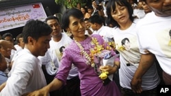 Pro-democracy leader Aung San Suu Kyi (C) holds her birthday gift as she makes her way through the crowd gathered at her National League for Democracy headquarters in Rangoon, June 19, 2011.