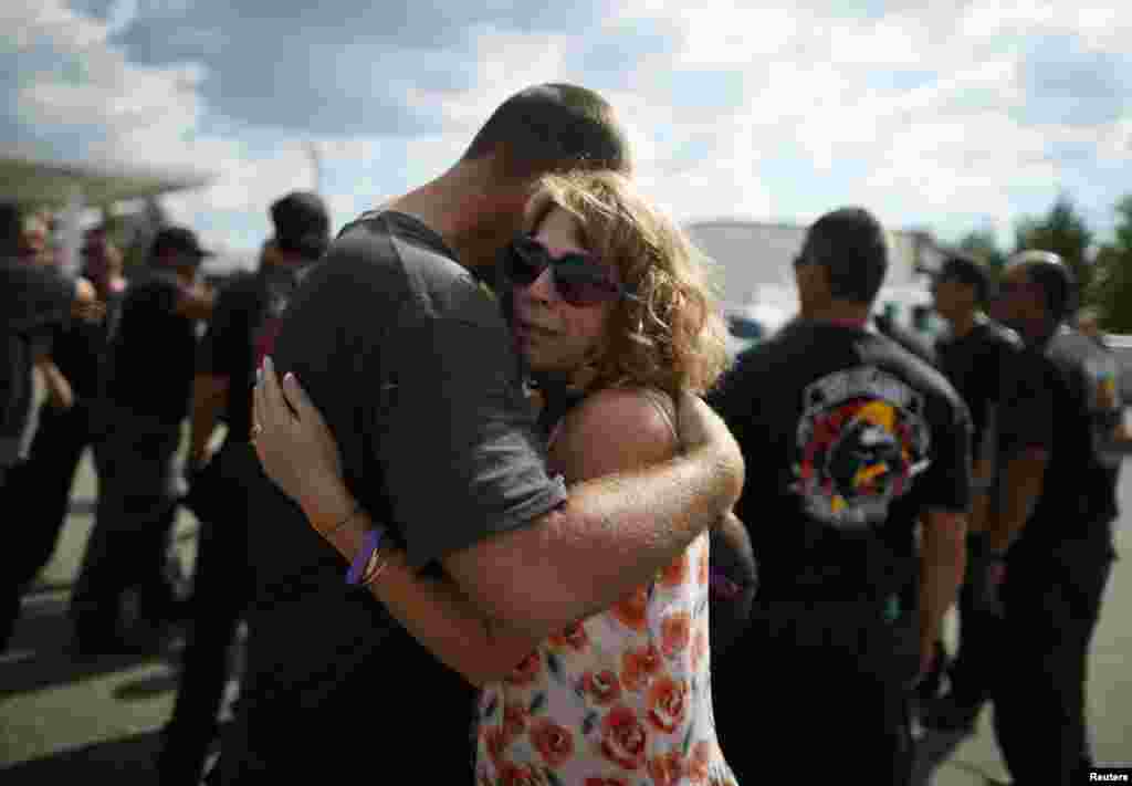 Anna Woyjeck, the mother of fallen firefighter Kevin Woyjeck, hugs a firefighter in front of a memorial dedicated to the 19 firefighters killed in the nearby wildfire in Prescott, Arizona, July 8, 2013. 