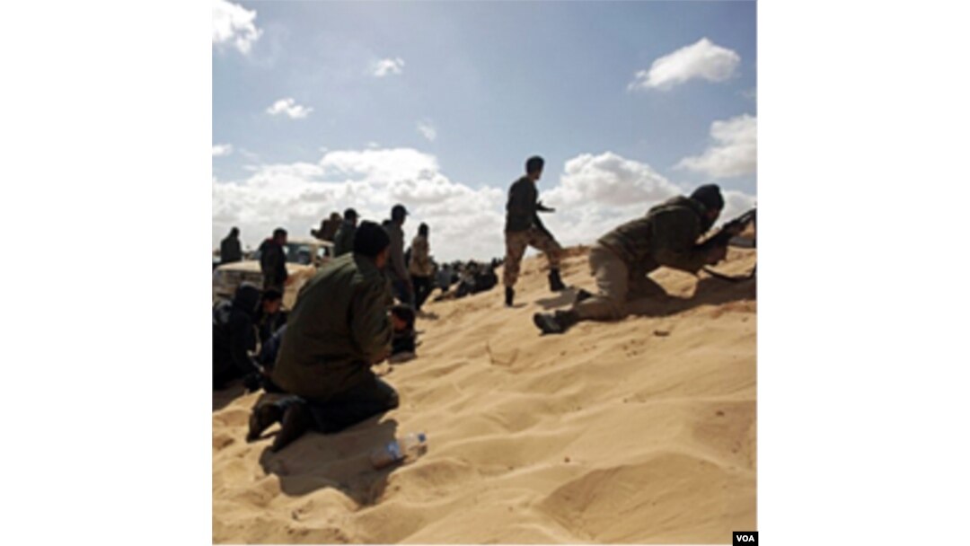 Para pemberontak Libya mencari perlindungan dalam bentrokan dengan pasukan pro-Gaddafi di kota Ajdabiya (21/3).