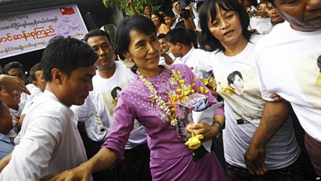 Pro-democracy leader Aung San Suu Kyi (C) holds her birthday gift as she makes her way through the crowd gathered at her National League for Democracy headquarters in Rangoon, June 19, 2011.