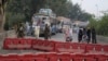 Police officers stand guard on an entry point to a road leading to Islamabad, which has been closed by authorities due to a planned rally by supporters of former Prime Minister Imran Khan's Pakistan Tehreek-e-Insaf party, in Lahore, Nov. 23, 2024.