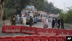 Police officers stand guard on an entry point to a road leading to Islamabad, which has been closed by authorities due to a planned rally by supporters of former Prime Minister Imran Khan's Pakistan Tehreek-e-Insaf party, in Lahore, Nov. 23, 2024.