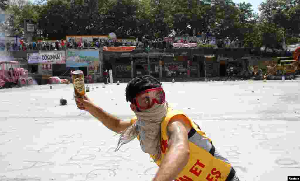 A protester throws a bottle at riot police in Taksim Square in Istanbul, June 11, 2013. 