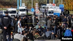 Bosnian and Croatian border police stand guard in front of migrants at Maljevac border crossing between Bosnia and Croatia near Velika Kladusa, Bosnia, October 24, 2018. REUTERS/Marko Djurica 