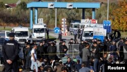 Polisi perbatasan Kroasia dan Bosnia berjaga di depan para migran di perbatasan Maljevac antara Bosnia dan Croatia dekat Velika Kladusa, Bosnia, 24 Oktober 2018. 