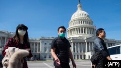 Pemandu wisata mengenakan masker, memandu sekelompok turis di Gedung Capitol, Washington DC, 9 Maret 2020.