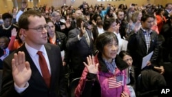 Inmigrantes toman el juramento de ciudadanía durante una ceremonia de naturalización en la Biblioteca Presidencial John F. Kennedy de Boston. Una campaña en la TV en la televisión habla de una “cadena potencialmente interminable” de inmigrantes que se inicia con la “amnistía” de una sola persona.