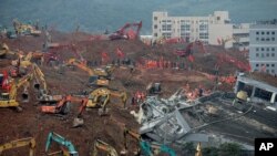 Rescuers using excavators dig the sea of soil to search for potential survivors near the damaged building following a landslide at a industrial park in Shenzhen, in south China's Guangdong province, Tuesday, Dec. 22, 2015.