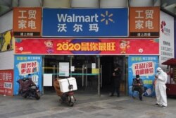 Workers are seen at an entrance to a Walmart store in Wuhan, the epicentre of the novel coronavirus outbreak, Hubei province, China, Feb.25, 2020.