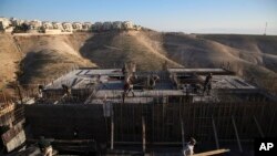 FILE - Palestinian laborers work at a construction site in a new housing project in the Israeli settlement of Maale Adumim, near Jerusalem, Feb. 7, 2017.