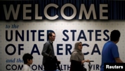 国际旅客抵达华盛顿国际机场，墙上的标语说“美利坚合众国欢迎你”。（2017年6月26日）