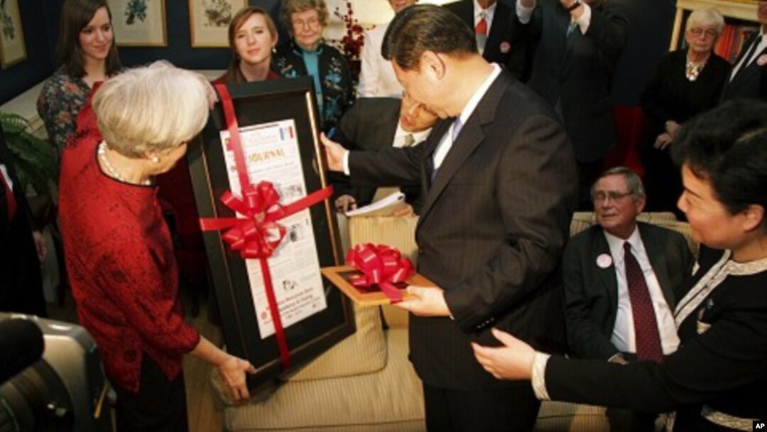 Sarah Lande (L) presents China's Vice President Xi Jinping a reproduction of the Muscatine Journal newspaper from 1985, when he first visited in Muscatine, Iowa, February 15, 2012.