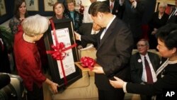 Sarah Lande (L) presents China's Vice President Xi Jinping a reproduction of the Muscatine Journal newspaper from 1985, when he first visited in Muscatine, Iowa, February 15, 2012.