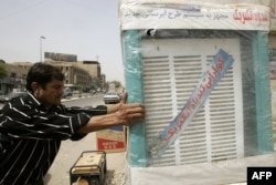 FILE - An Iraqi merchant receives a delivery of Iranian-made air coolers, at his shop in central Baghdad.