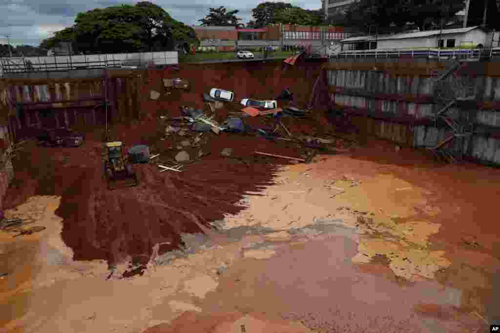 Vehicles lay at the bottom of a construction site after a road collapsed from heavy rains in the center of Brasilia, Brazil, Dec. 10, 2019.