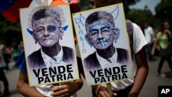 Government supporters hold defaced pictures of opposition Congressman Henry Ramos Allup, which read in Spanish "Country seller," as they march in Caracas, Venezuela, Sept. 11, 2017. Government supporters marched with pictures of opposition leaders blaming them for United States' sanctions against Venezuela and asked the attorney general to prosecute them.