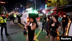 Asistentes a la fiesta caminan entre ambulancias en el lugar donde decenas de personas resultaron heridas en una estampida durante un festival de Halloween en Seúl, Corea del Sur, el 30 de octubre de 2022. REUTERS/Kim Hong-ji 