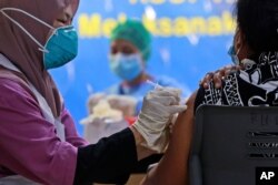 A health worker gives a jab of the Sinovac COVID-19 vaccine to a woman during a vaccination campaign at the Adam Malik Hospital in Medan, North Sumatra, Indonesia, June 30, 2021.