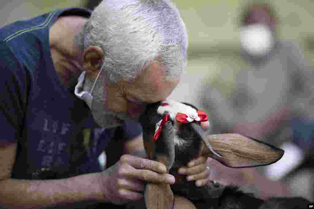 An elderly man caresses a goat named Jurema, wearing ribbons on her ears, at the Maria Vieira Bazani nursing home in Rio de Janeiro, Brazil.