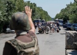 A member of the Ukrainian State Border Guard Service gives a sign to people to stop as they approach a checkpoint at the contact line between pro-Russian rebels and Ukrainian troops in Mayorsk, Ukraine July 3, 2019.