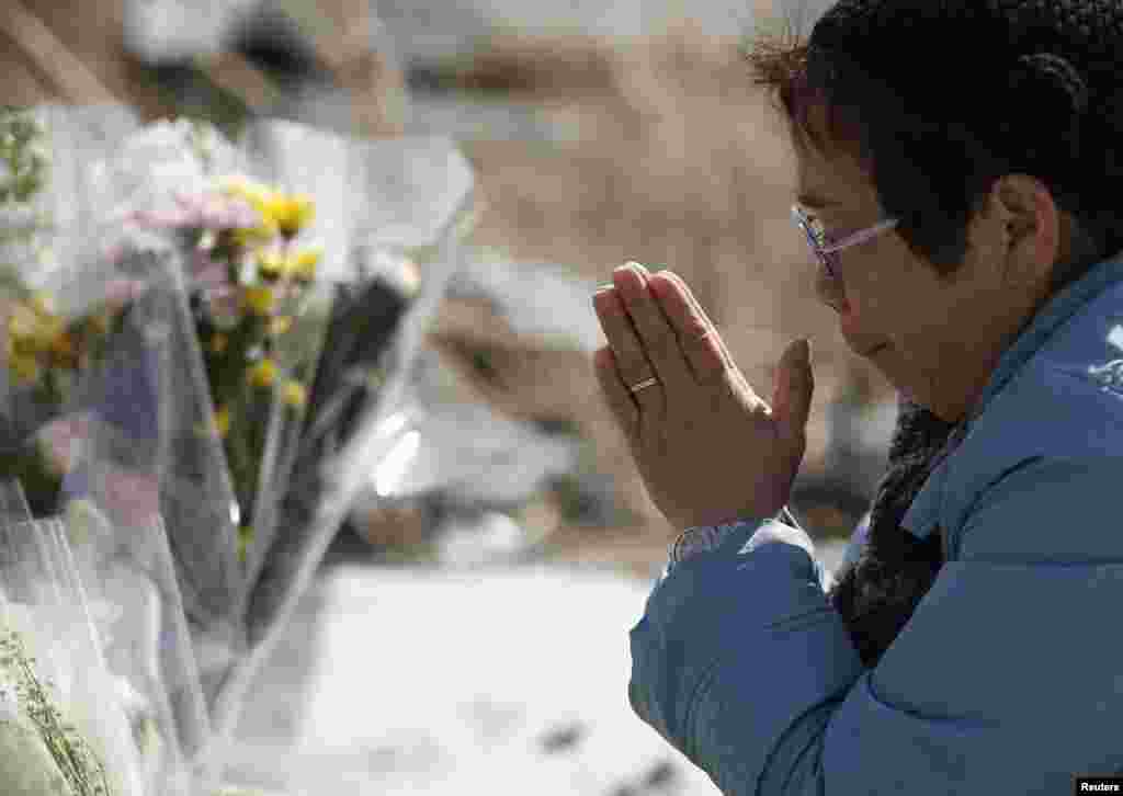 Seorang perempuan berdoa bagi para korban gempa bumi dan tsunami di kota Namie, prefektur Fukushima (11/3).