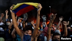 Protesters react in front of a fire burning at the entrance of a building, housing the magistracy of the Supreme Court of Justice and a bank branch, during a rally against Venezuela's President Nicolas Maduro, in Caracas, Venezuela, June 12, 2017.