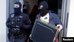 FILE - German special police leave a house in Berlin Nov. 15, 2016. German police launched dawn raids on mosques, apartments and offices in 10 German states, and the government banned a group it accused of trying to recruit fighters for Islamic State, the interior ministry said.