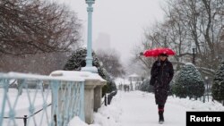 一名婦人在波士頓走過一個鋪滿白雪的公園