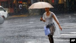 FILE - A woman holding an umbrella crosses a street in heavy rain in Tokyo's Ginza shopping district, Wednesday, Sept. 9, 2015.
