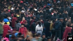 FILE - People rush to catch trains at a station in Beijing. The number of the city's permanent residents reached 21.707 million last year, 22,000 fewer than the previous year, Xinhua said. 