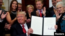 FILE - President Donald Trump smiles after signing an executive order to make it easier for Americans to buy bare-bone health insurance plans and circumvent Obamacare rules, at the White House in Washington, Oct. 12, 2017.