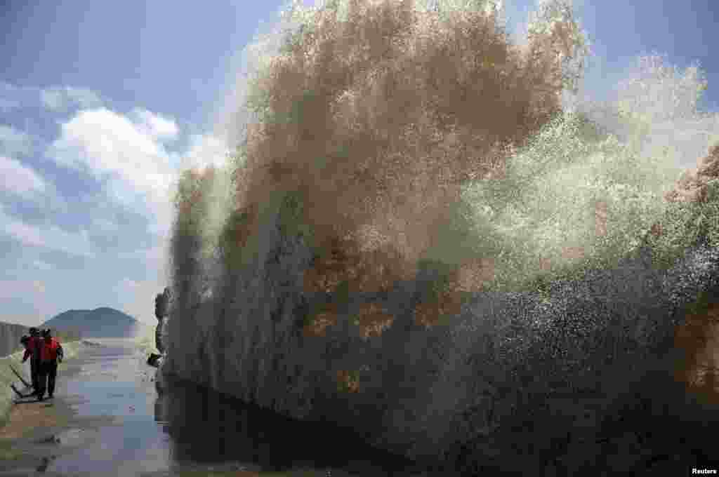 Frontier soldiers look up at a wave while checking a seawall as Typhoon Soulik approaches in Wenling, Zhejiang province, China. China braced for the impact of Soulik as the toll of dead and missing from torrential rain across a broad swath of the country climbed beyond 200.