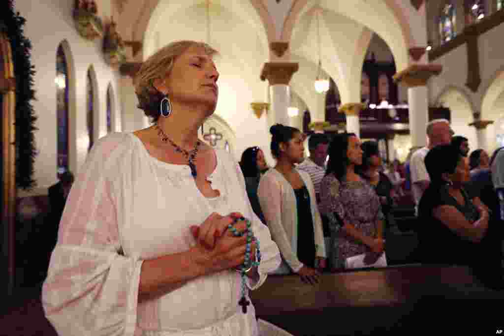 Jemaat berdoa dalam misa untuk para polisi yang tewas dan terluka di Katedral Guadalupe di Dallas, Texas (9/7). (AP/Gerald Herbert)