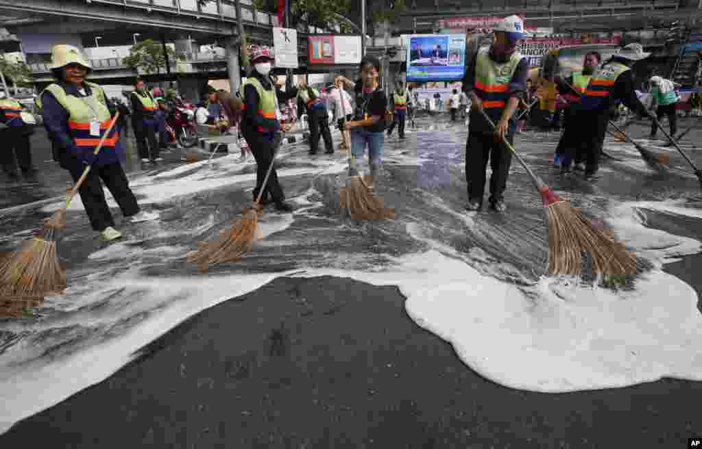 Street cleaners brush the main anti-government protest site with detergent and brooms in Bangkok, Feb. 5, 2014.