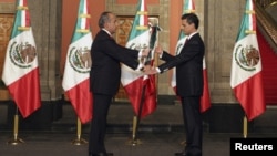 Presiden Meksiko Felipe Calderón (kiri) menyerahkan bendera Meksiko kepada Presiden baru Enrique Peña Nieto pada upacara pelantikan di Mexico City (1/12). 