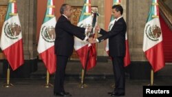 El presidente saliente, Felipe Calderón (izq.), entrega a Enrique Peña Nieto la enseña nacional durante la toma de posesión.