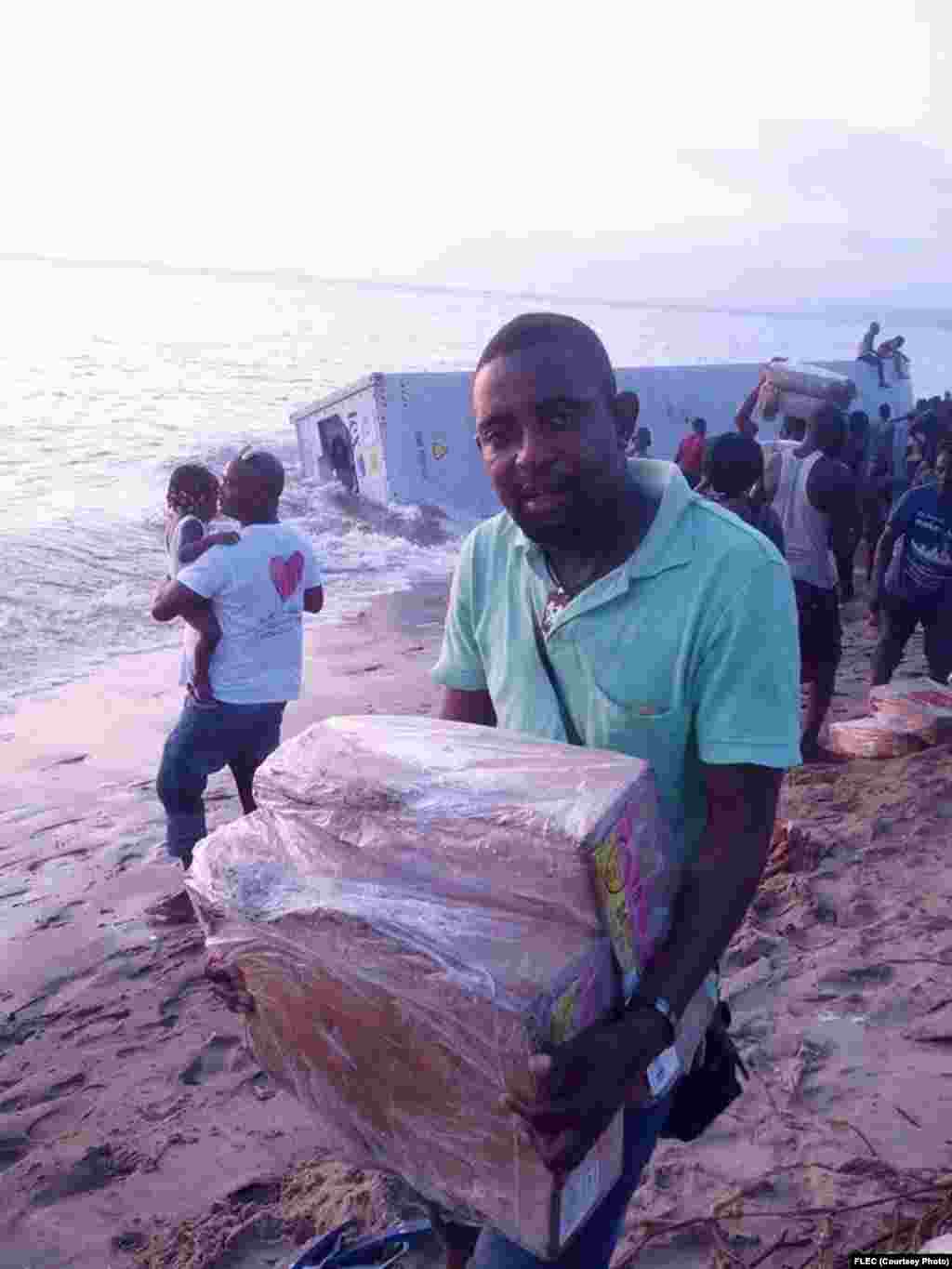 Angola, Cabinda - Depois de os contentores terem dado à praia, os moradores da zona acorreram à mercadoria do navio afundando ao largo da costa. Maio 16, 2014