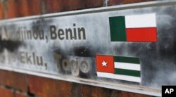 FILE - The flags of the nations of Benin and Togo, the west African homes of the survivors of the slave ship Clotilda, remain on display on a monument at what was the Africatown Welcome Center in Mobile, Ala., Jan. 29, 2019. The center was destroyed by Hurricane Katrina in 2005.