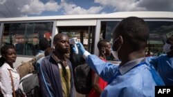 Un personnel du Centre Biomédical Rwandais (RBC) contrôle les passagers dans une station de bus à Kigali, au Rwanda, le 22 mars 2020.