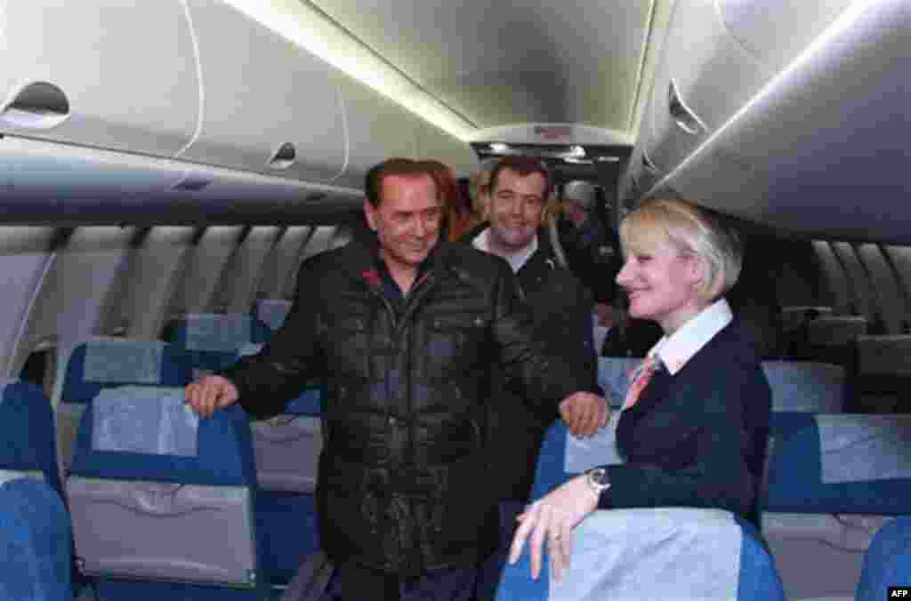Italian Prime Minister Silvio Berlusconi, front, and Russian President Dmitry Medvedev, back, examine a new Russian passenger plane, Sukhoi Superjet 100, at the airport in the Black Sea resort of Sochi, southern Russia, Friday, Dec. 3, 2010. Italian
