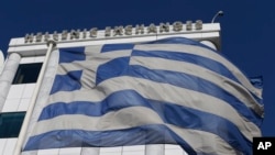 A Greek flag waves outside the Stock Exchange in Athens on Monday, Dec. 29, 2014. Greece was forced Monday to call early national elections, stoking financial concerns as investors worry the main opposition party will win _ and want to renege on the coun