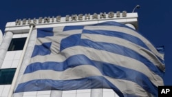 FILE - A Greek flag flutters outside the Stock Exchange in Athens Dec. 29, 2014. Decisions, made in the throes of a growing debt crisis,
contributed to a program that proved unsustainable, an IMF review has found.