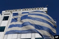 FILE - A Greek flag waves at the Stock Exchange in Athens. Greece will have early national elections Saturday, stoking investor concerns that the main opposition party will win and will want to renege on bailout terms.