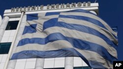 A Greek flag waves outside the Stock Exchange in Athens on Monday, Dec. 29, 2014.