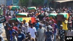 People carry coffins during the funeral after street protests and unrest that resulted in nine deaths in Conakry, on Nov. 4, 2019. 